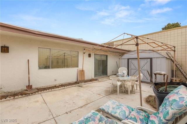 view of patio / terrace with an outdoor structure, a storage shed, and outdoor dining space
