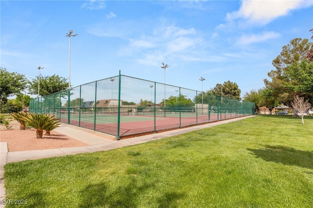 view of tennis court featuring a lawn and fence