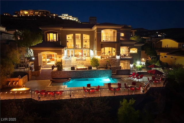 1520 Macdonald Ranch Dr, Henderson, NV 89012 - back of house at twilight featuring a balcony, a hot tub, a patio area, and a fenced in pool