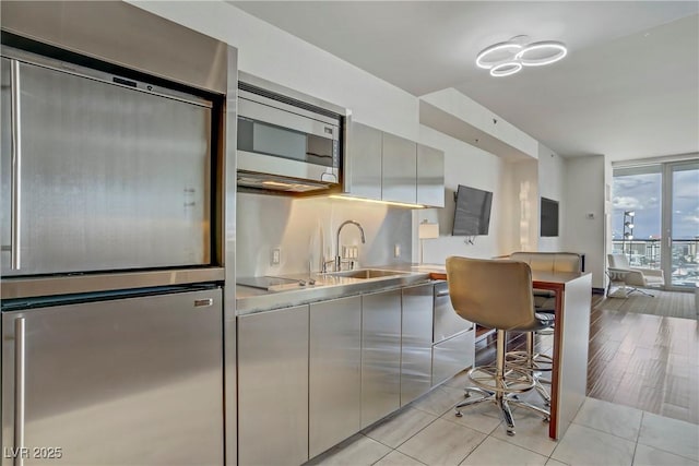 4381 W Flamingo Rd Unit 27308, Las Vegas, NV 89103 - kitchen featuring appliances with stainless steel finishes, a sink, light tile patterned floors, gray cabinetry, and modern cabinets