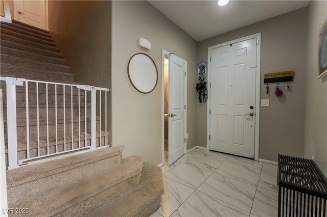 foyer with baseboards, marble finish floor, and stairway