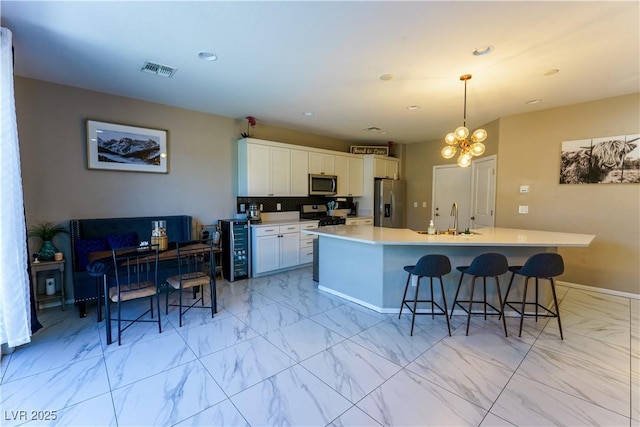 kitchen featuring a kitchen breakfast bar, a sink, marble finish floor, stainless steel appliances, and visible vents