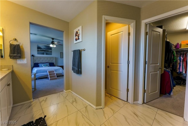corridor with marble finish floor, baseboards, visible vents, and light carpet