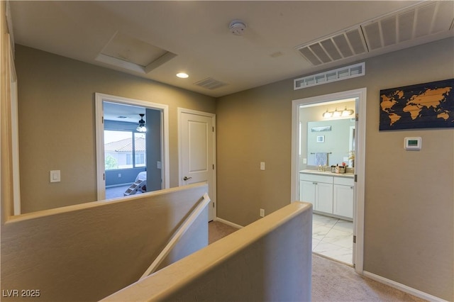 hall with attic access, visible vents, and baseboards