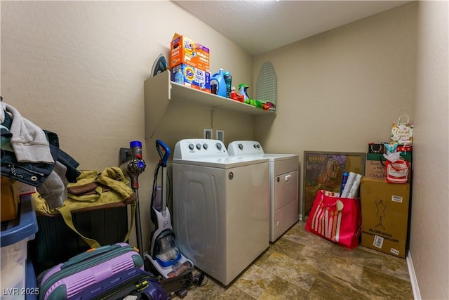 clothes washing area with washing machine and dryer, stone finish flooring, and laundry area