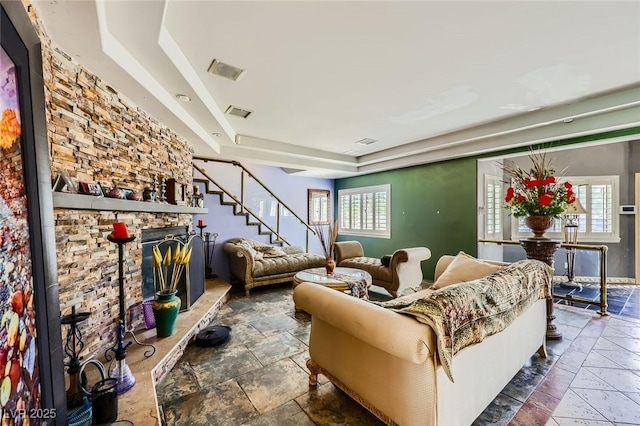 7165 Mira Monte Cir, Las Vegas, NV 89120 - living area featuring a stone fireplace, stairs, a tray ceiling, stone finish floor, and visible vents