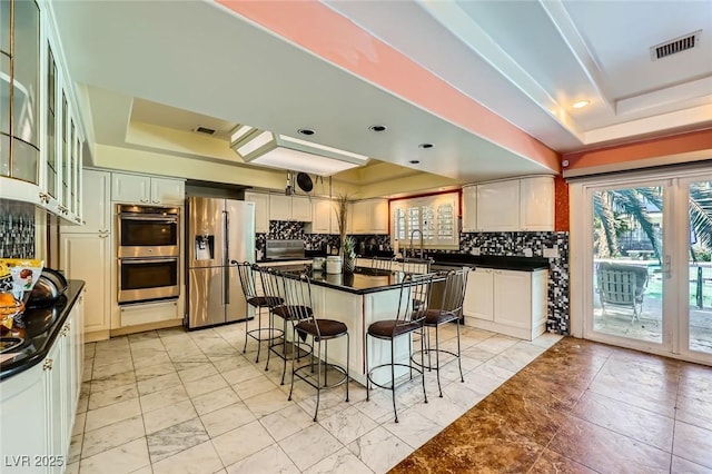 7165 Mira Monte Cir, Las Vegas, NV 89120 - kitchen with a raised ceiling, a kitchen bar, appliances with stainless steel finishes, and dark countertops