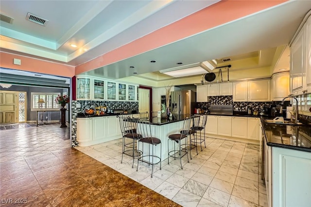 7165 Mira Monte Cir, Las Vegas, NV 89120 - kitchen with a breakfast bar, stainless steel fridge, a raised ceiling, backsplash, and visible vents