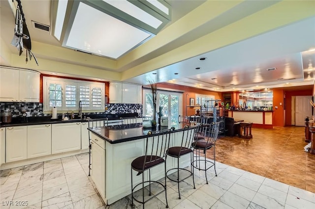 7165 Mira Monte Cir, Las Vegas, NV 89120 - kitchen with decorative backsplash, a kitchen breakfast bar, a tray ceiling, and dark countertops