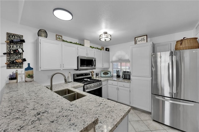 kitchen with light tile patterned floors, white cabinetry, a sink, stainless steel appliances, and light stone countertops