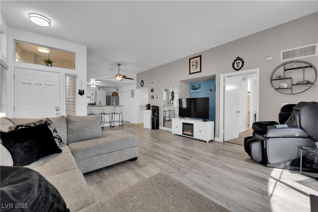 living area with visible vents, ceiling fan, and light wood finished floors