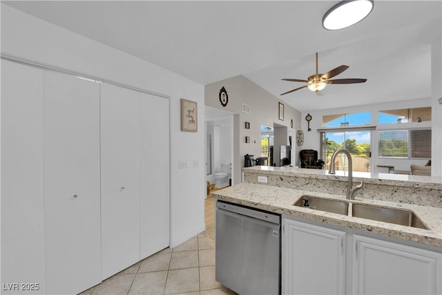kitchen with lofted ceiling, light tile patterned floors, stainless steel dishwasher, a sink, and open floor plan