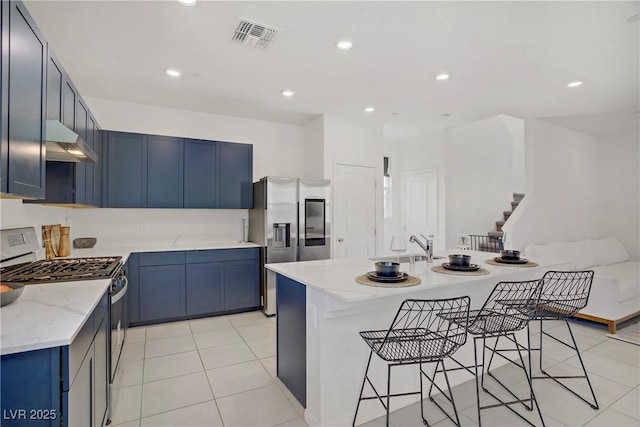 5692 Tinar St, Las Vegas, NV 89113 - kitchen with a kitchen breakfast bar, under cabinet range hood, visible vents, blue cabinets, and appliances with stainless steel finishes