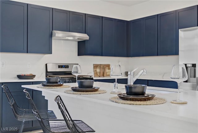 5692 Tinar St, Las Vegas, NV 89113 - kitchen featuring blue cabinetry, under cabinet range hood, stainless steel appliances, and light countertops