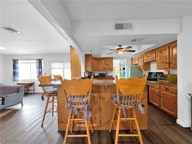 kitchen with dark wood-style floors, appliances with stainless steel finishes, visible vents, and plenty of natural light
