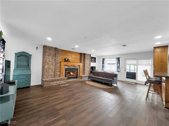 living room featuring baseboards, a brick fireplace, wood finished floors, and recessed lighting