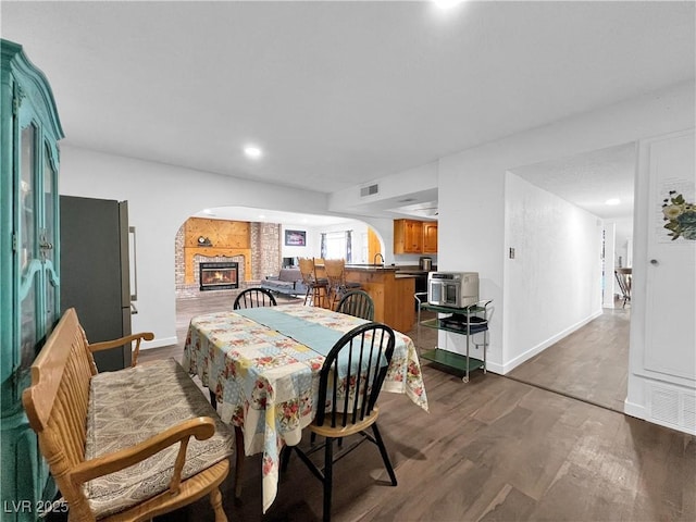 dining space featuring recessed lighting, wood finished floors, visible vents, arched walkways, and baseboards