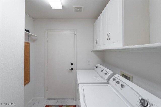 laundry room with baseboards, separate washer and dryer, visible vents, and cabinet space