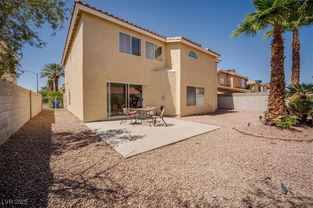 back of property with a tiled roof, stucco siding, a patio area, and a fenced backyard
