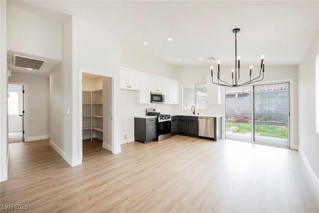 kitchen featuring a notable chandelier, a sink, stainless steel appliances, light wood-type flooring, and visible vents