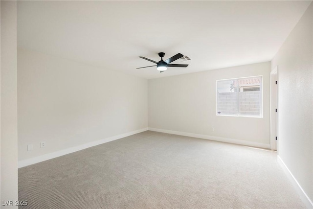 empty room with light colored carpet, a ceiling fan, and baseboards