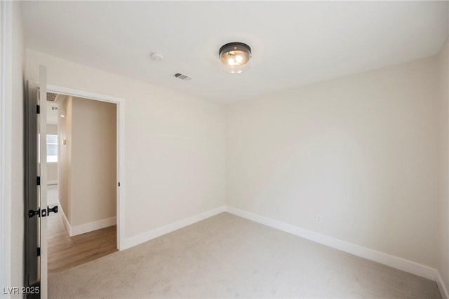 empty room with baseboards, light colored carpet, and visible vents