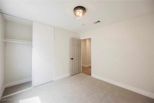 unfurnished bedroom with a closet, baseboards, carpet flooring, and visible vents