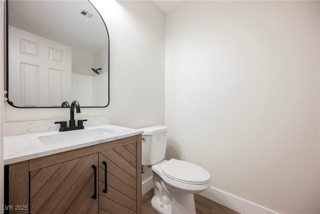 bathroom with visible vents, wood finished floors, baseboards, vanity, and toilet
