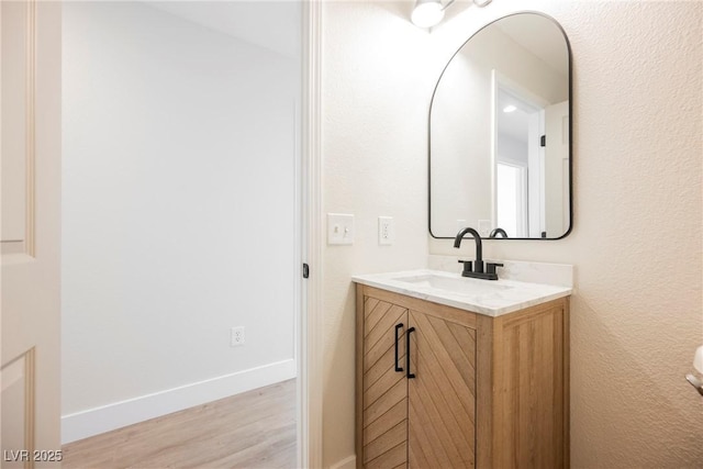 bathroom with vanity, baseboards, and wood finished floors