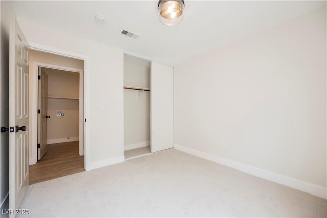 unfurnished bedroom featuring baseboards, a closet, visible vents, and light carpet
