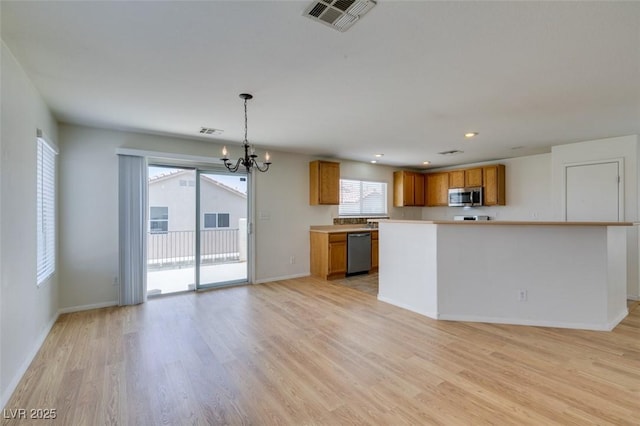 11668 Tierney Creek Dr, Las Vegas, NV 89183 - kitchen featuring stainless steel appliances, a chandelier, brown cabinets, light countertops, and light wood finished floors