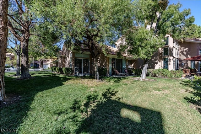 rear view of house with a yard and stucco siding