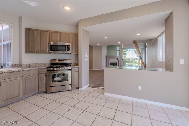 kitchen with light tile patterned flooring, stainless steel appliances, a fireplace, baseboards, and recessed lighting
