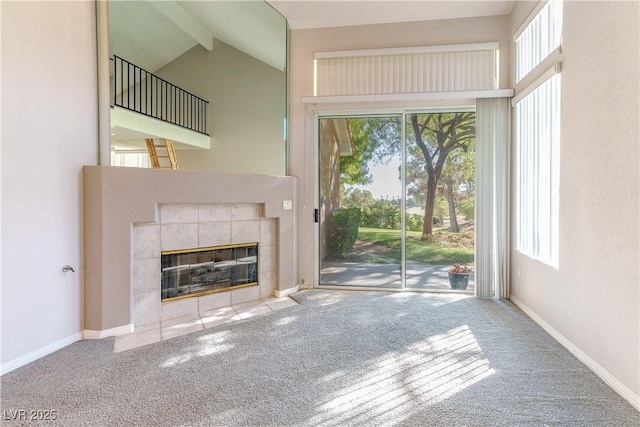 unfurnished living room featuring lofted ceiling with beams, baseboards, carpet flooring, and a tile fireplace