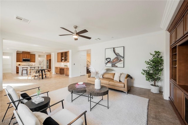 living room with ceiling fan, baseboards, crown molding, and visible vents
