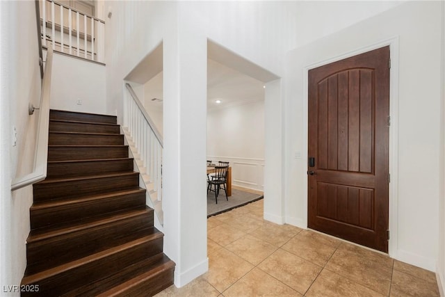 foyer with stairs, light tile patterned floors, and crown molding