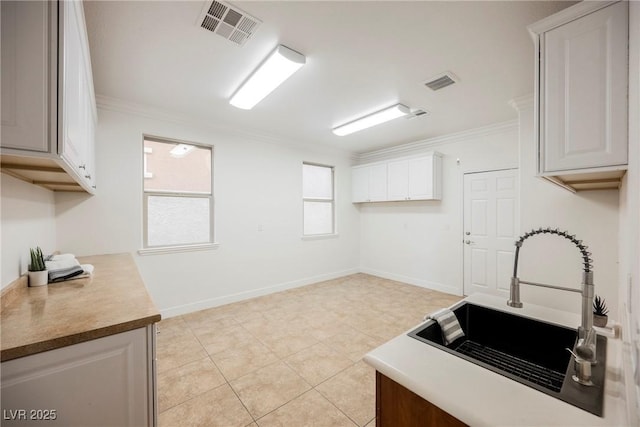 kitchen featuring visible vents, light tile patterned floors, ornamental molding, and a sink