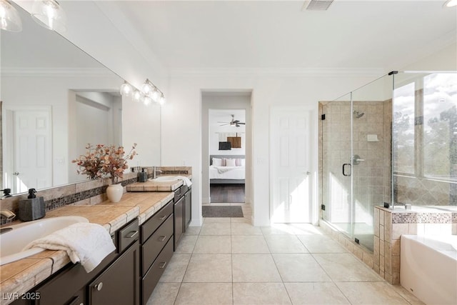 ensuite bathroom featuring tile patterned floors, a garden tub, a sink, and a stall shower