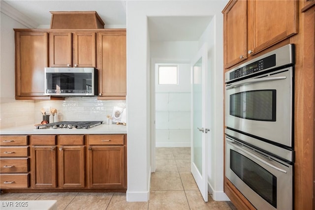 kitchen with light countertops, brown cabinetry, and appliances with stainless steel finishes