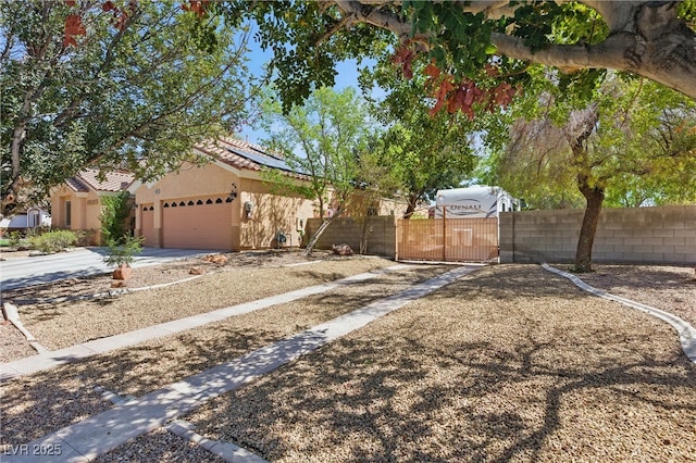 view of front of house featuring roof mounted solar panels, a gate, stucco siding, fence private yard, and a garage