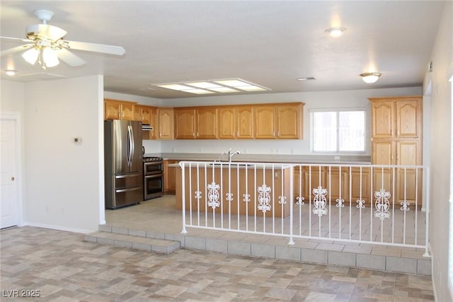 kitchen with a sink, baseboards, ceiling fan, light countertops, and appliances with stainless steel finishes