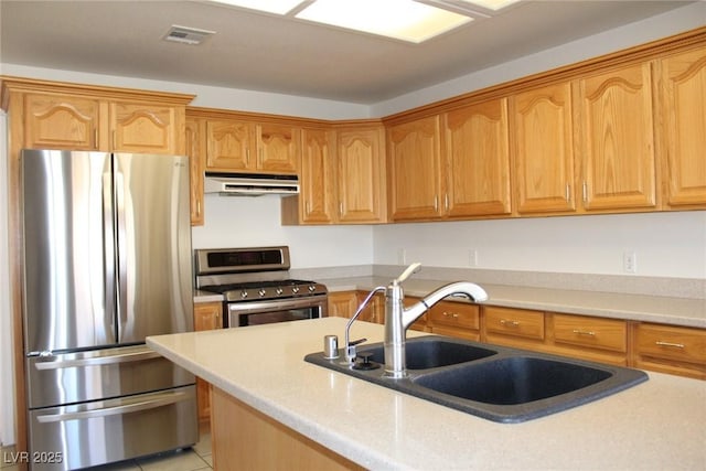 kitchen with a sink, light tile patterned floors, appliances with stainless steel finishes, under cabinet range hood, and visible vents
