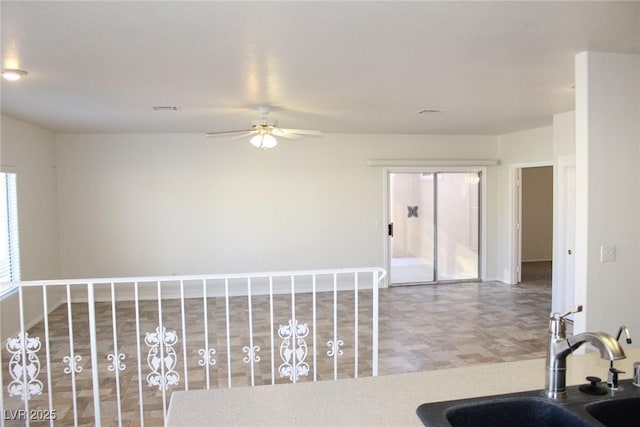 interior space featuring visible vents, a ceiling fan, baseboards, and a sink