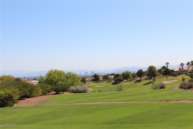 view of community with golf course view, a lawn, and a mountain view