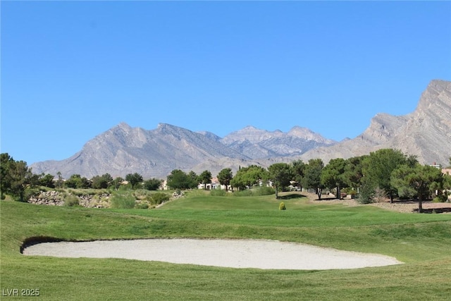 view of property's community with a lawn, view of golf course, and a mountain view