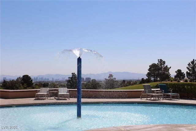 community pool with a patio and a mountain view
