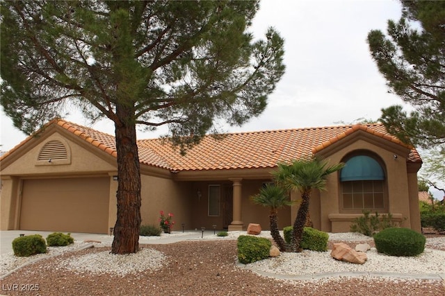 mediterranean / spanish-style home with an attached garage, a tile roof, and stucco siding