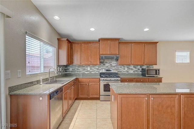7822 Whitlocks Mill Ave, Las Vegas, NV 89147 - kitchen with stainless steel appliances, a sink, under cabinet range hood, backsplash, and light stone counters