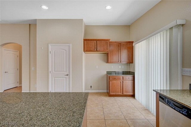7822 Whitlocks Mill Ave, Las Vegas, NV 89147 - kitchen with stainless steel dishwasher, brown cabinetry, arched walkways, light tile patterned floors, and recessed lighting