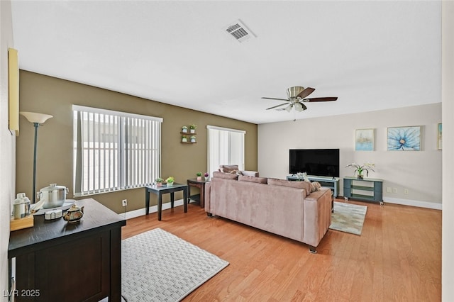 living room with light wood-style flooring, visible vents, ceiling fan, and a healthy amount of sunlight